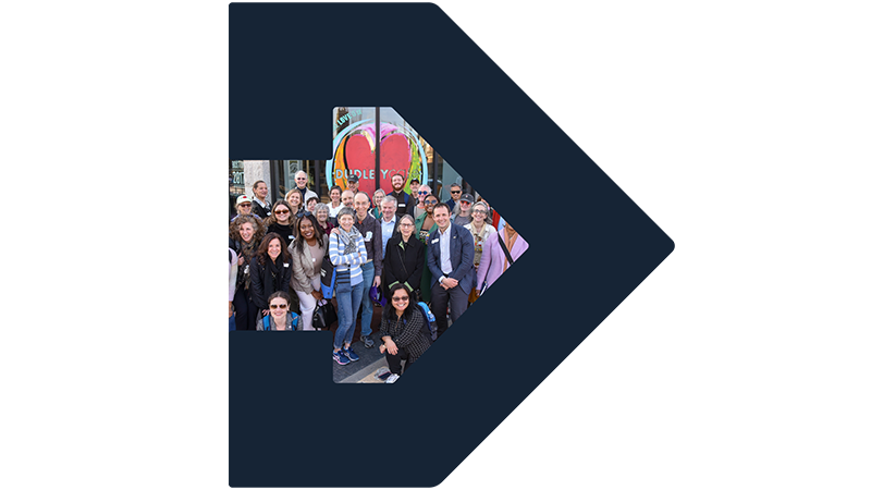 Photo of a big TBF walking tour group standing in front of a cafe, framed by TBF arrow icon