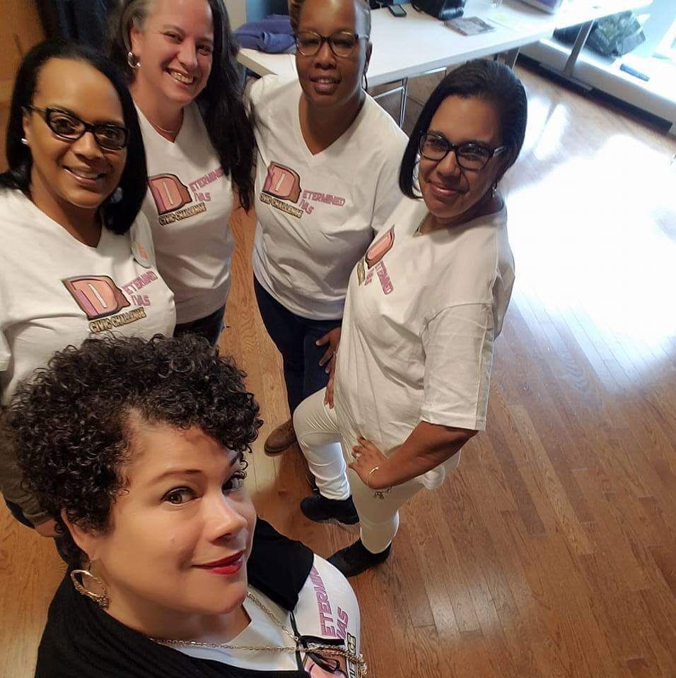 Julia Mejia standing in front of 4 women who are part of the Determined Divas team. They're all smiling and wearing matching white t-shirts with the Determined Divas logo on them,