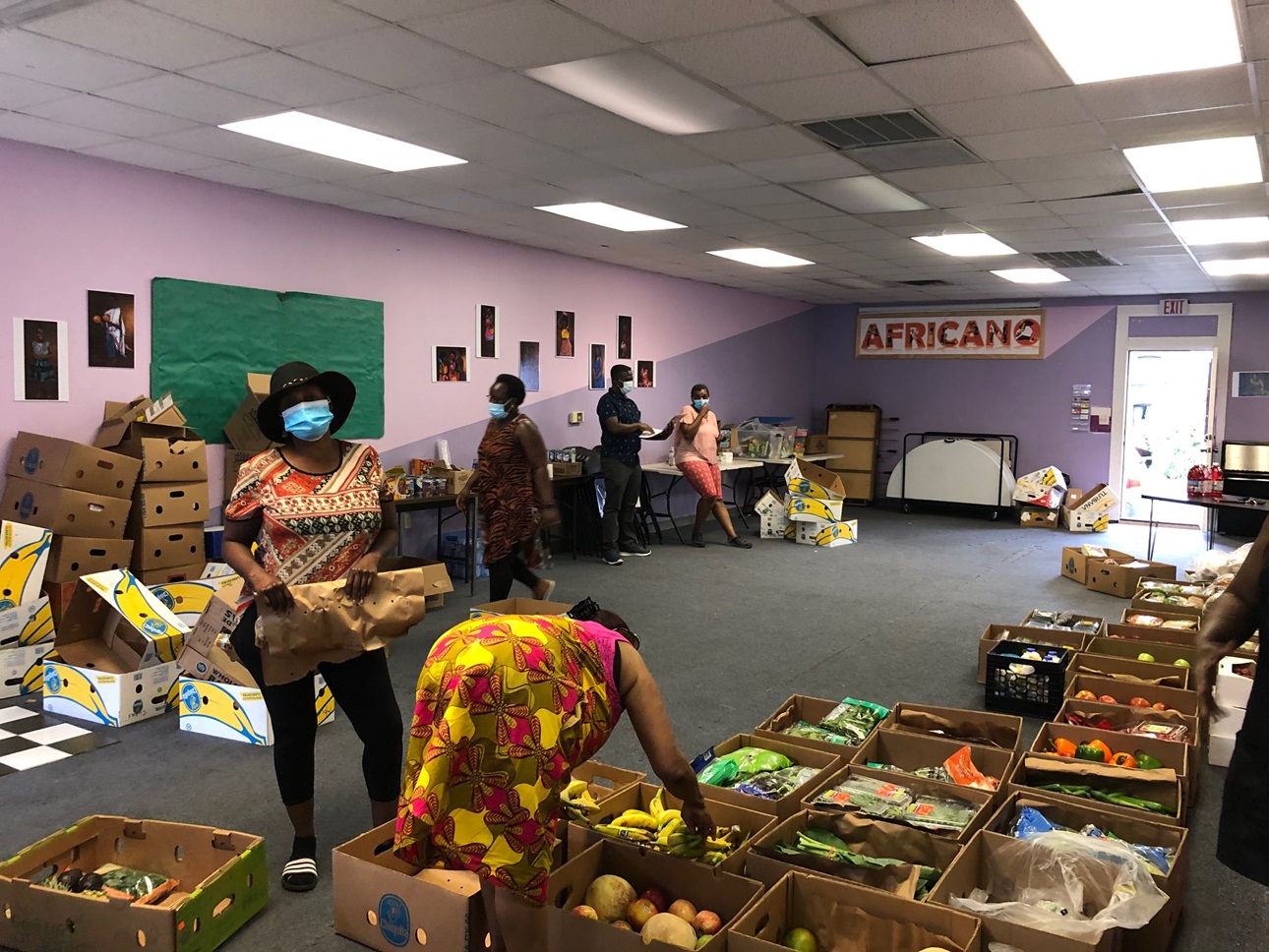 Women at Africano Waltham standing among boxes full of produce for a food drive.
