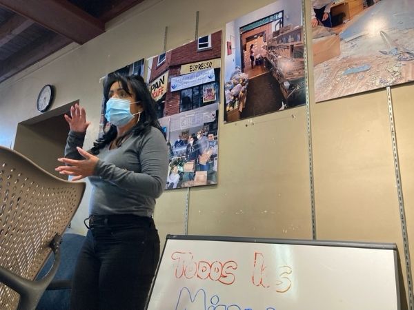 Gladys Vega inside Chelsea Collaborative headquarters, speaking and standing.