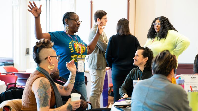 Group of casually dressed people at conference, talking animatedly.