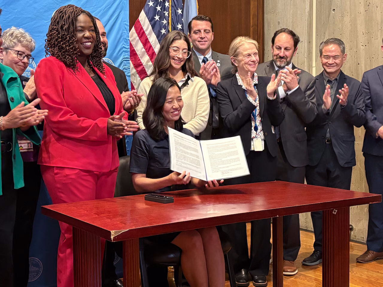 Boston Mayor Michelle Wu (C) surrounded by members of City Council and advocates signs a new city ordinance that prioritizes turning surplus city property into affordable housing. Wu signed the ordinance during a news conference at City Hall on Wednesday, Oct. 22, 2025. John L. Micek/MassLive