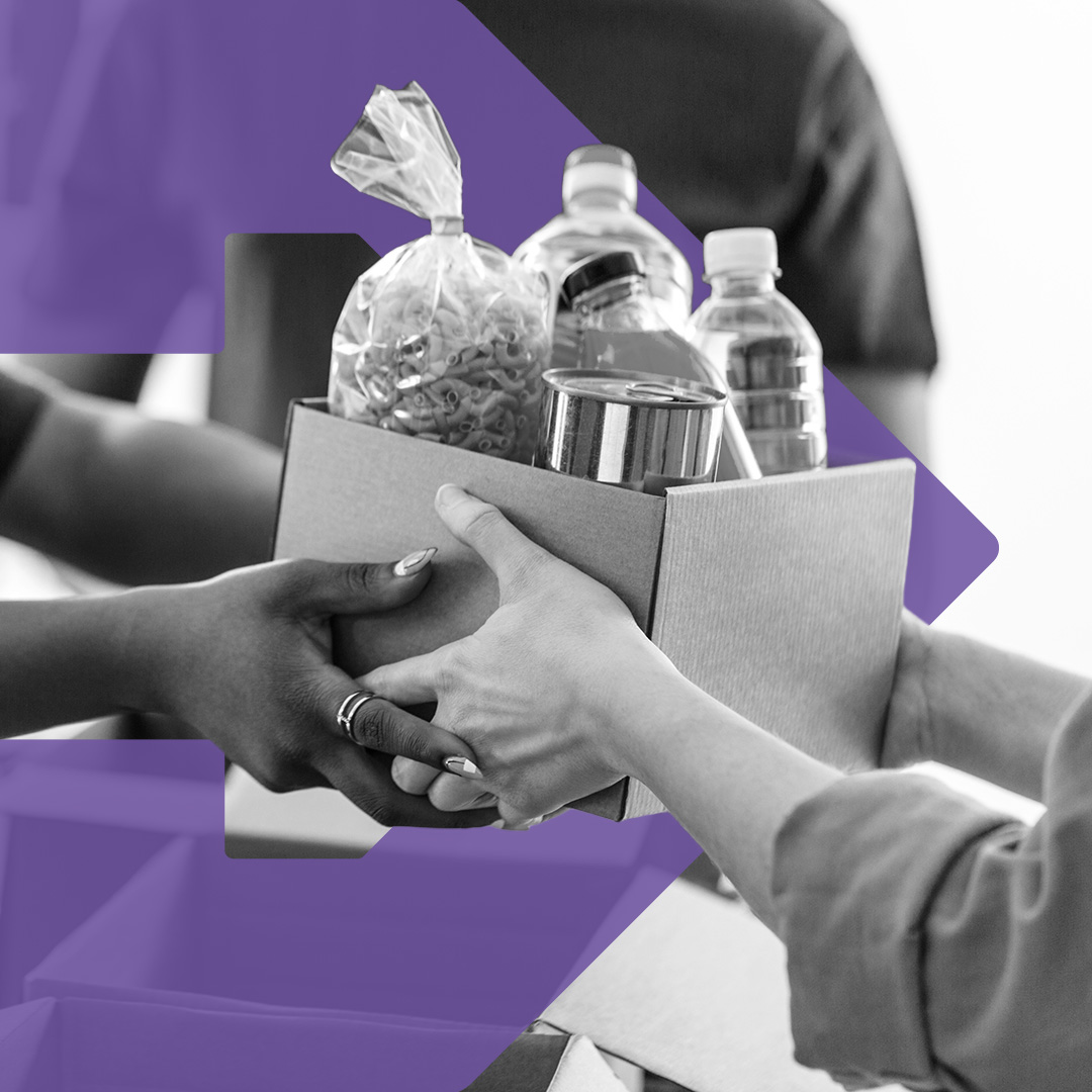 a woman passes a box filled with food to another person accepting the box.