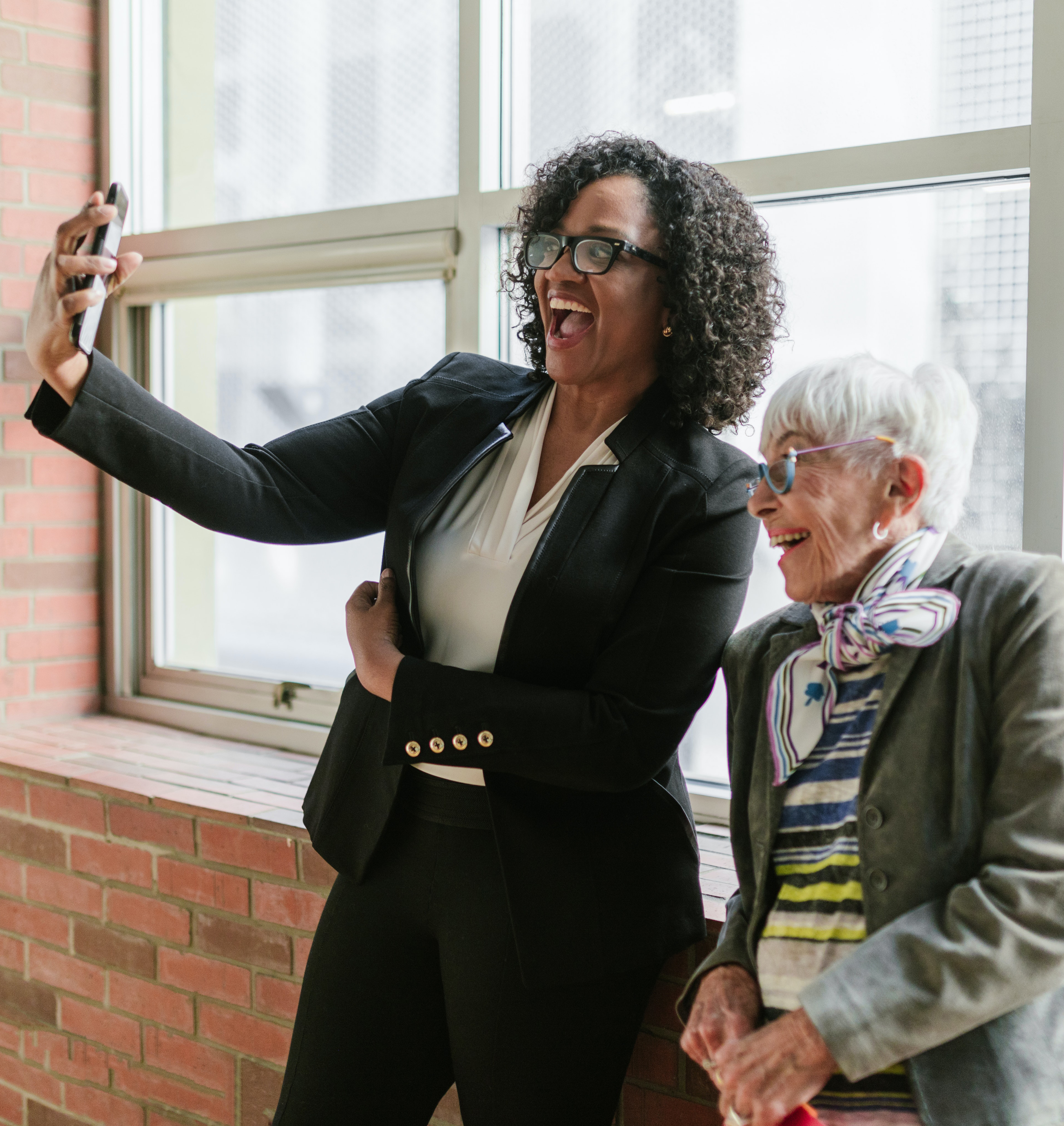 younger black and older white businesswomen take selfie