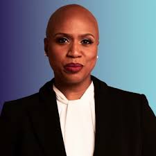 Headshot of Ayanna Pressley. She is wearing a white shirt and black blazer. The background is a horizontal indigo-turquoise gradient.