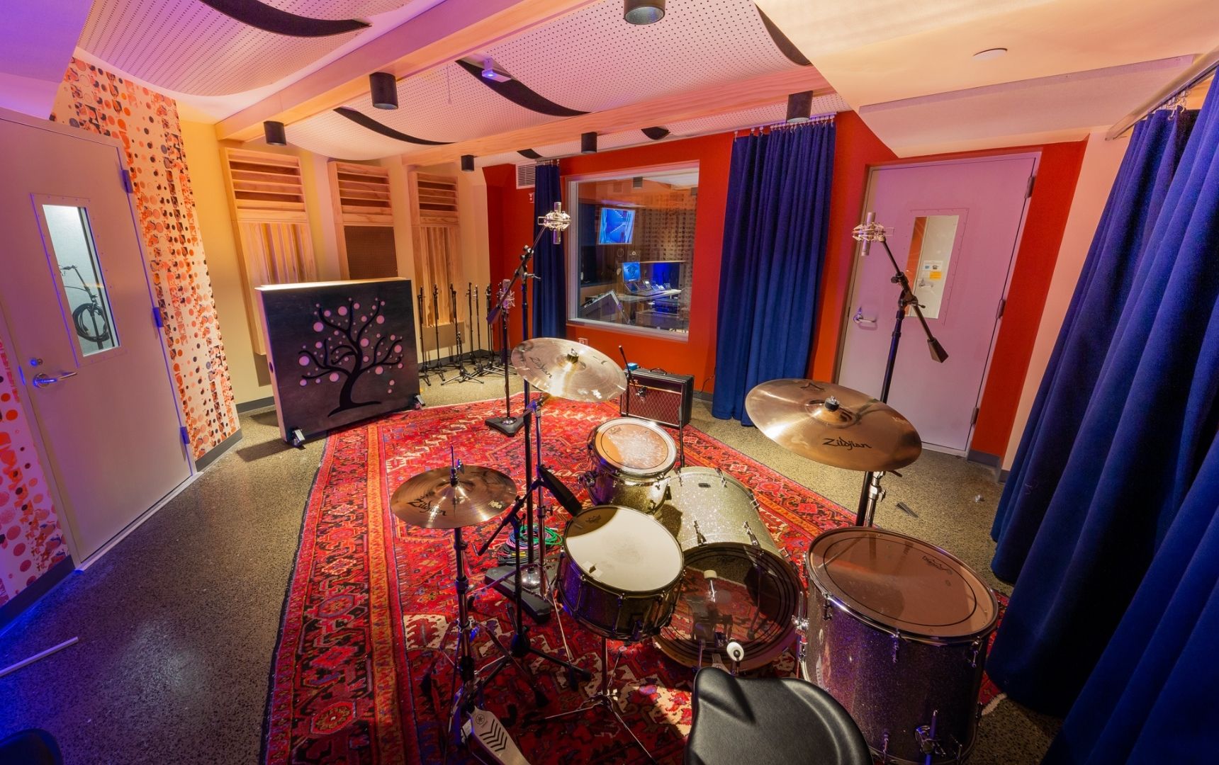 Studio B at The Record Co. - a warmly lit recording studio with a red carpet and a drum set in the center of the room. Photo by Jenny Bergman.