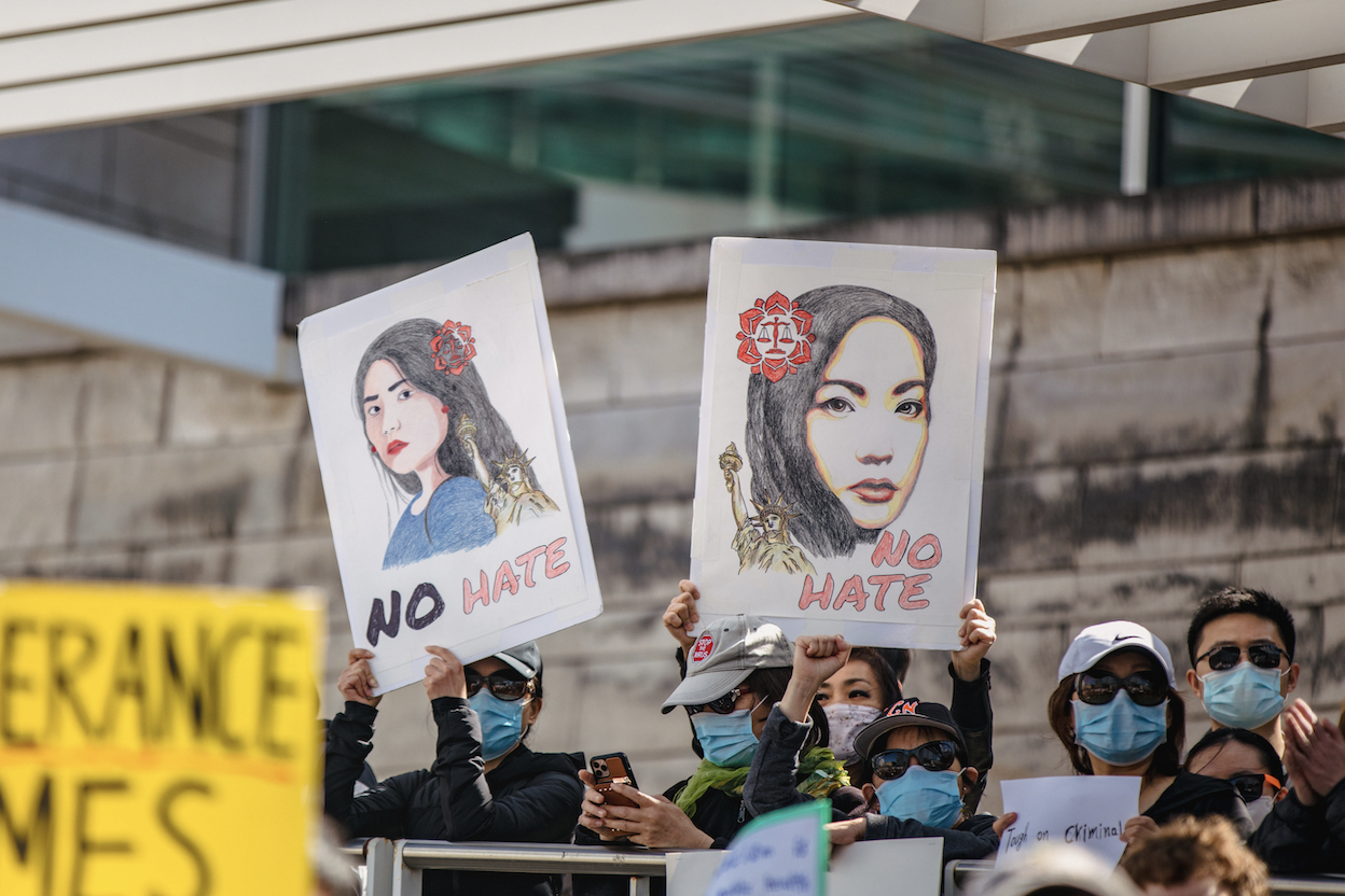 In center photo, two drawings of women of Asian descent with the words "NO HATE" written below them. These drawings are being held up by people in a rally outdoors.