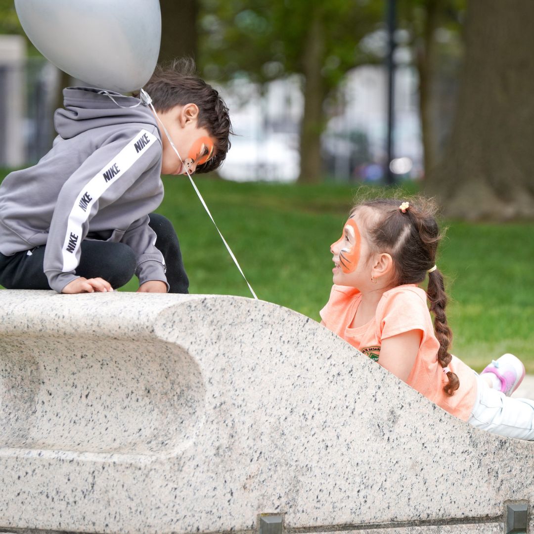 Two children with their faces painted play together at a TBF community event in East Boston