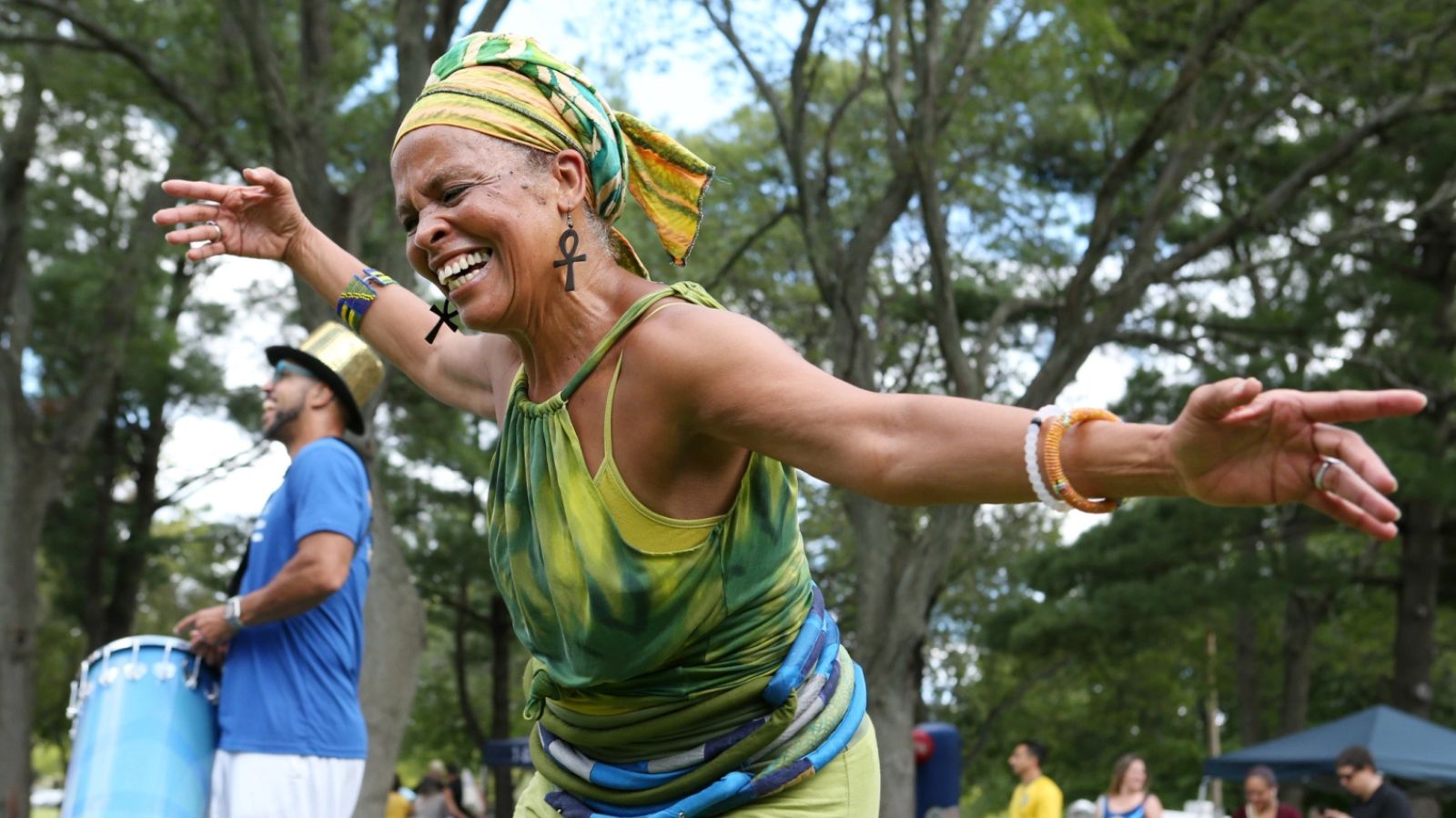 A Brazilian woman dances outside in a park with a crowd of people behind her