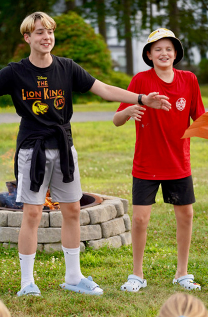 Two campers stand by a firepit