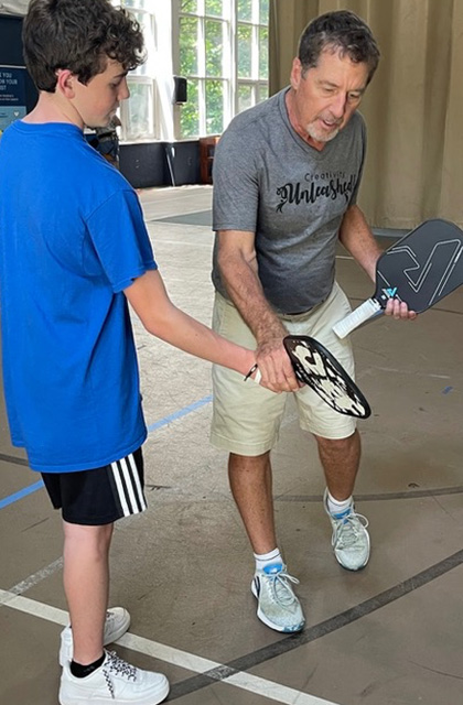 Richard Mades instructs a camper on pickleball