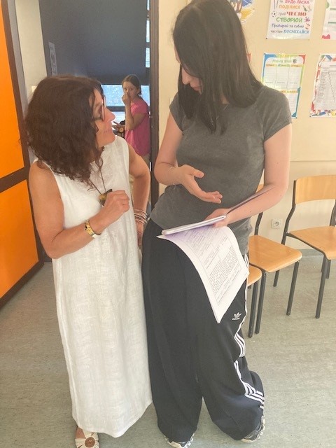 Two women stand in a classroom looking at each other