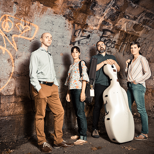 Members of Sheffield Chamber Players stand in a tunnel painted with graffiti. 