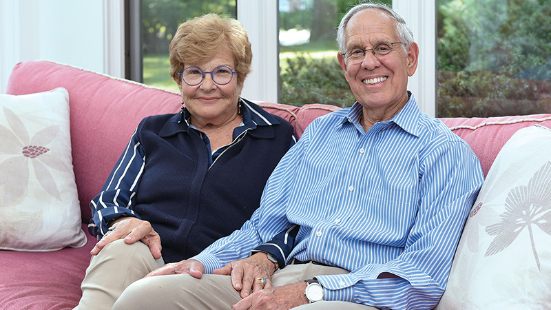 The Adlers sit on a couch smiling for a photo