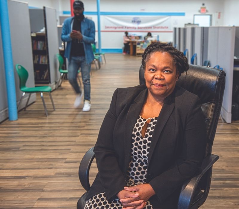 Dr. Geralde Gabeau sitting in an office chair with her hands folded in her lap. She's smiling at the camera. In the background is an office with hardwood floors and cubicles.