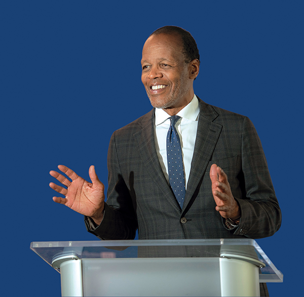 Lee Pelton stands onstage at a podium giving a speech