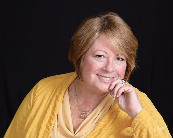 A headshot style photo of Karen Ansara, a white woman with chin-length blonde hair