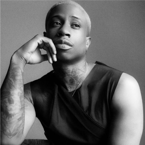 A black and white photo of ANSON RAP$. He has one hand raised to his mouth and looks pensive.