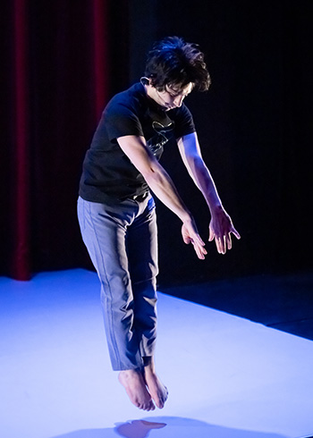 A man, Alex Davis, performs onstage.