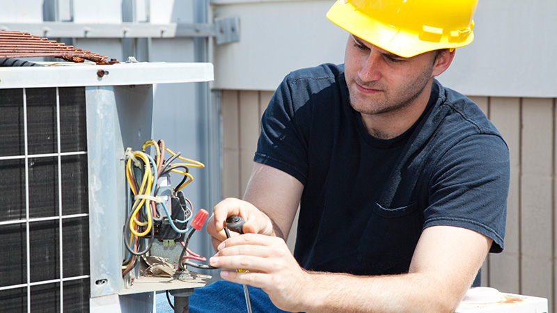 A man looks at exposed wires on an electrical device outdoors