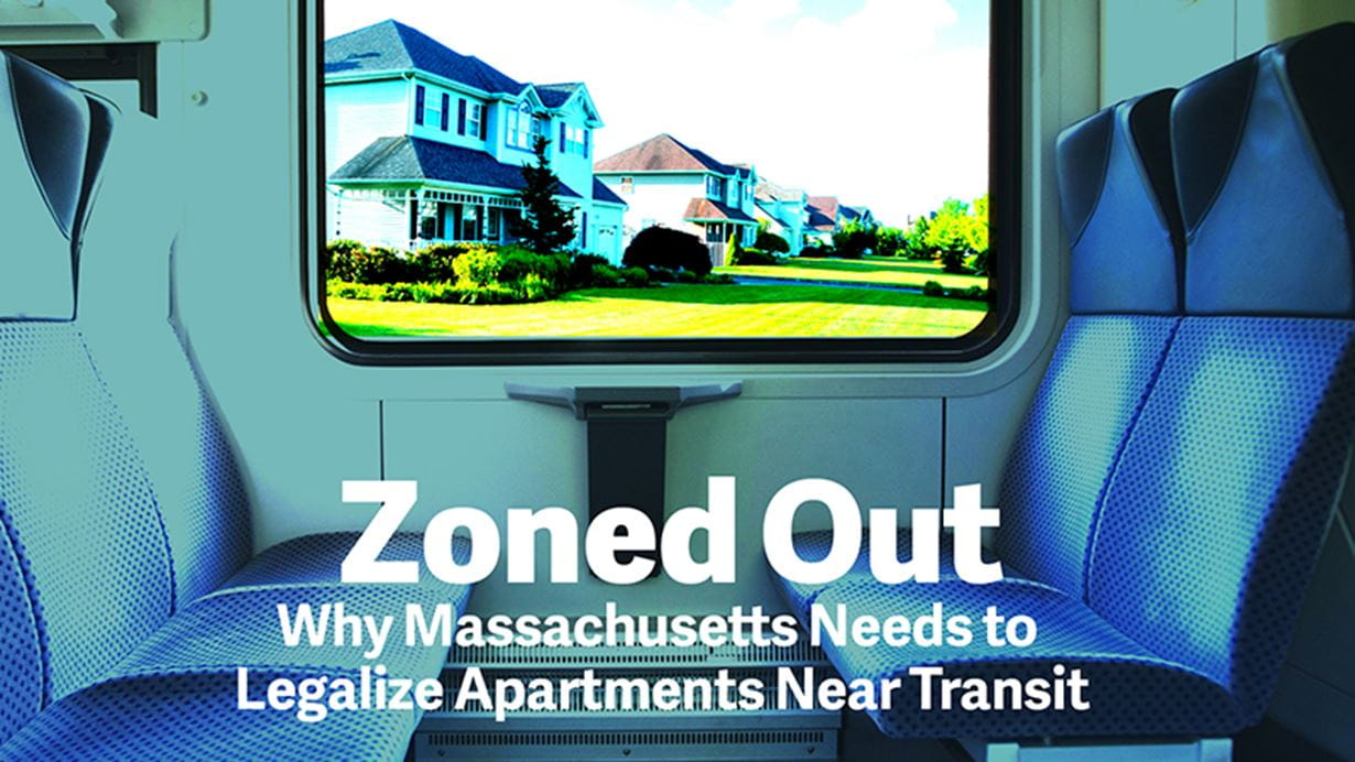 hown through a train window, a row of large, suburban houses with green lawns and driveways gradually disappears into the background.