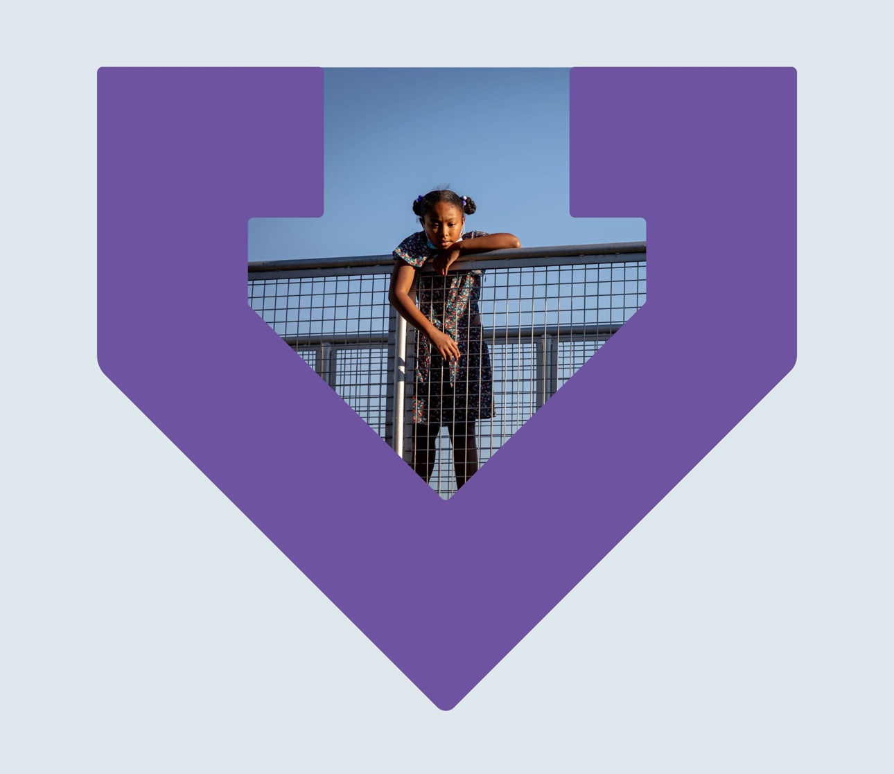 A photo of a young black girl standing at a fence looking very serious inside a purple TBF arrow