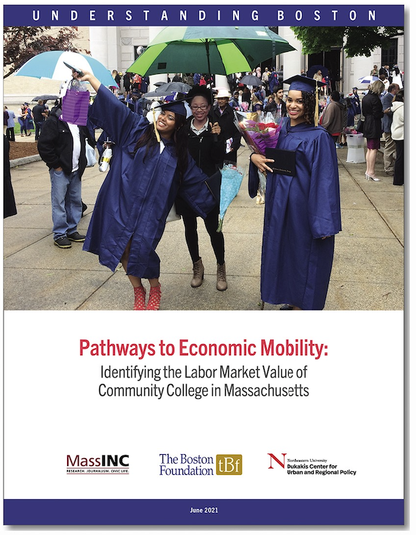 A picture of three women of color on graduation day. Two are wearing purple graduation robes, smiling, one of whom has her hands in the air. The third woman is standing in between the two graduates, wearing a black coat and holding an umbrella. Graduates and their families are in the background.