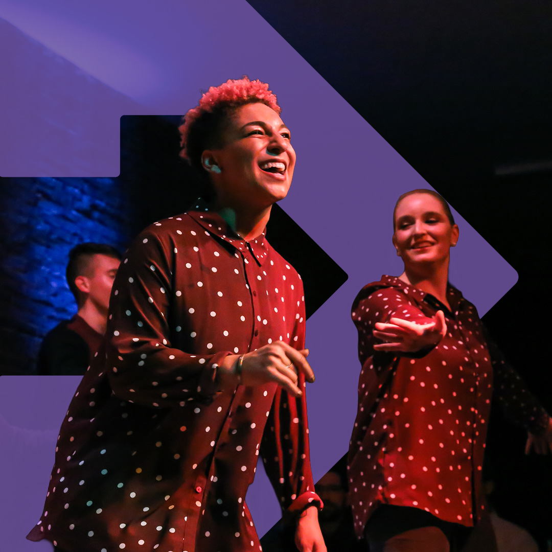  a group of dancers performs onstage with a close up of one dancer with a huge smile.