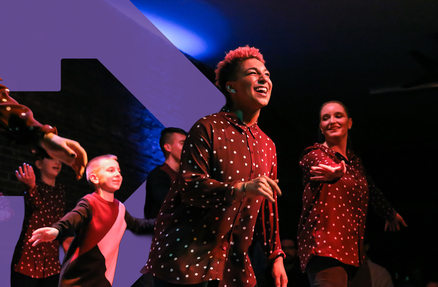  a group of dancers performs onstage with a close up of one dancer with a huge smile.